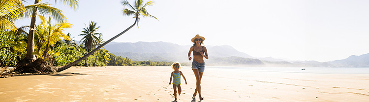 Mor og barn løper på eksotisk strand
